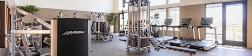 A gym with a variety of equipment including treadmills, weights, and exercise machines.