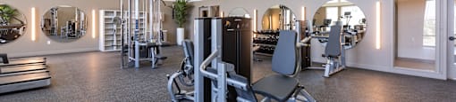 A gym with a variety of equipment including treadmills, weights, and exercise machines.