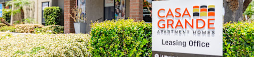 A sign for Casa Grande Apartment Homes Leasing Office in front of a building.