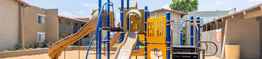 A playground with a yellow slide and a blue and yellow play structure.