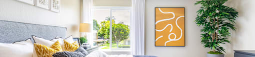 A bedroom with a large bed and a painting on the wall.