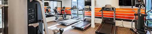 a gym with cardio equipment and a television on the wall at CASA GRANDE APARTMENT HOMES, Cypress, California