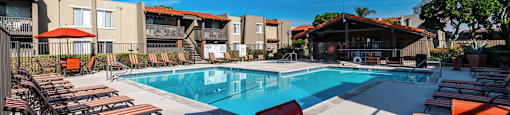 a pool with chairs and an umbrella next to a swimming pool at CASA GRANDE APARTMENT HOMES, Cypress, 90630