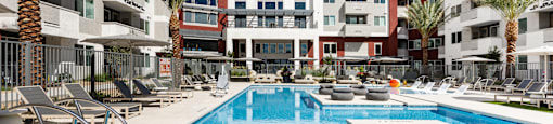A large swimming pool in front of a multi-story apartment building.