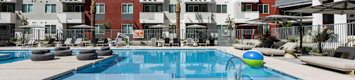 A swimming pool in front of a multi-story apartment building.