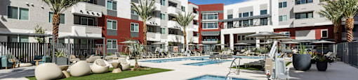 A pool in front of a multi-story apartment building.