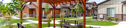 a wooden pergola with a bench in a courtyard at Arcadia Townhomes, Roy