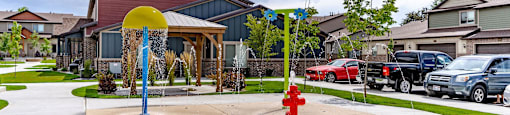 a red fire hydrant on a sidewalk in front of a building at Arcadia Townhomes, Roy, UT