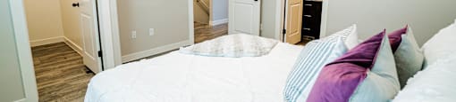 a bedroom with a large bed and a door to a bathroom at Arcadia Townhomes, Roy Utah