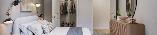 A bedroom with a large bed and a clothing rack in the background.