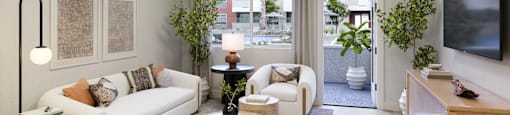 A living room with a white couch, a wooden coffee table, and a flat-screen TV mounted on the wall.