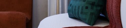 A white couch with a red pillow and a green pillow on it.