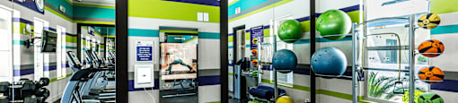 A gym with a variety of equipment including weights and exercise balls.