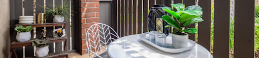 A patio with a table and chairs and a fence.