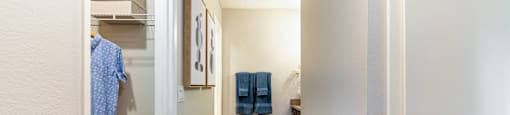A hallway with a coat hanging on the wall and a towel hanging on the rack.
