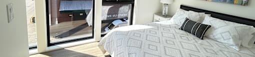 a bedroom with a bed and two large windows at DOCK 59 APARTMENTS, PORTLAND, OR, 97209