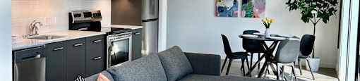 a living room with a couch table and chairs and a kitchen in the background at DOCK 59 APARTMENTS, PORTLAND, OR