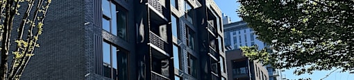A street view of a row of modern buildings with cars parked on the side.