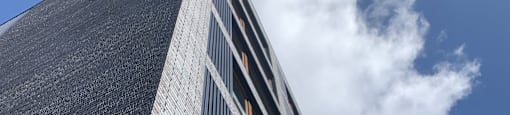 A tall building with a black facade and a large window on the side.