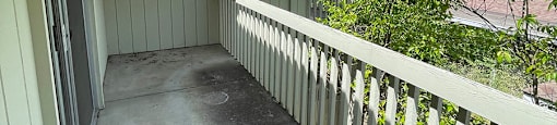 a porch with a white fence and a house in the background at OTAVON APARTMENTS, Novato