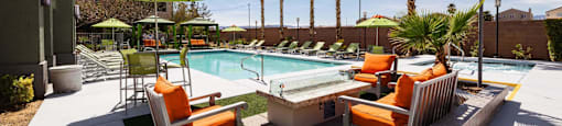 a pool with chairs and umbrellas next to a resort style pool at EVERETT APARTMENT HOMES, Las Vegas, NV