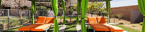 a lounge area with orange lounge chairs and green umbrellas at EVERETT APARTMENT HOMES, Nevada, 89113