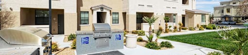 A view of an outdoor patio with a grill and picnic table  at EVERETT APARTMENT HOMES, Las Vegas, 89113