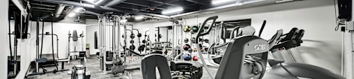 A gym with a variety of equipment including treadmills, weights, and exercise machines.