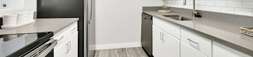 A kitchen with white cabinets and a black refrigerator.