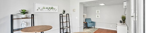 A room with a wooden table and chairs, a ladder, and a framed picture on the wall.