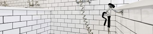 A white tiled shower with a black drain.