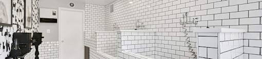 A bathroom with white tiles on the walls and a white sink.