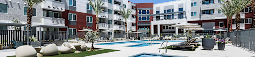 A pool surrounded by palm trees and a building.