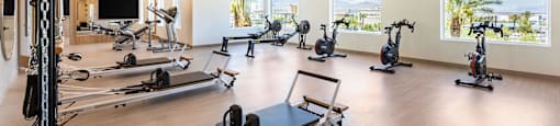 A spacious gym with a variety of equipment including treadmills, stationary bikes, and a rowing machine.