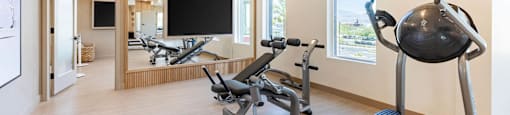 A gym with a variety of equipment including a stationary bike, a rowing machine, and a weight bench.