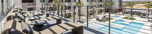 A patio with a table and chairs overlooks a pool.