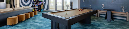 A billiard table is in the middle of a room with a blue carpet.