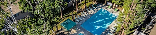 a backyard with a swimming pool and a patio with tables and chairs at SERRANO HIGHLANDS APARTMENT HOMES, Lake Forest, CA, 92630-7006