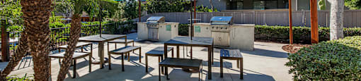 a patio with tables and umbrellas and a grill at SERRANO HIGHLANDS APARTMENT HOMES, Lake Forest, 92630-7006