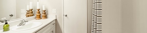 a bathroom with a sink and a shower and a mirror at SYCAMORE GREENS APARTMENT HOMES, Vista