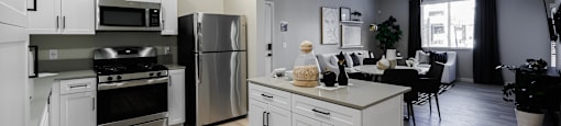 an open kitchen and dining room with stainless steel appliances and white cabinets at SYNC APARTMENT HOMES, North Las Vegas, NV