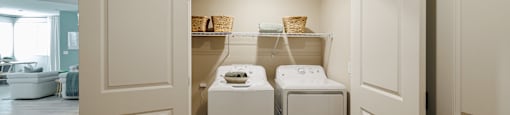 a washer and dryer closet in a laundry room with white doors at SYNC APARTMENT HOMES, Nevada, 89084