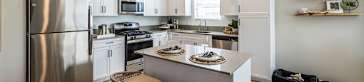 an open kitchen with stainless steel appliances and a island with two stools at SYNC APARTMENT HOMES, Nevada