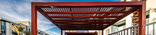 A patio with a pool and a wooden pergola.