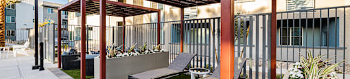 A patio with a bench and a table under a roof.