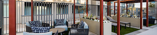 A patio area with a red pergola and grey couches.