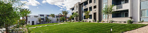 modern apartment buildings with a grassy area and a gravel pathway at BASE APARTMENT HOMES, LAS VEGAS, NV 89166