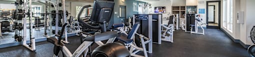 a gym with weights and cardio equipment in a building with glass doors at BASE APARTMENT HOMES, Nevada