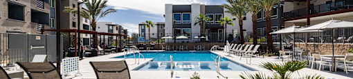 a swimming pool at a hotel with chairs and umbrellas at BASE APARTMENT HOMES, LAS VEGAS, 89166