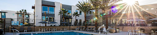 A sunny day at the pool with a building in the background.